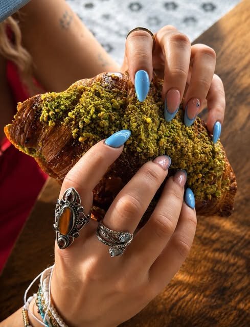 Hands holding a fresh pistachio croissant