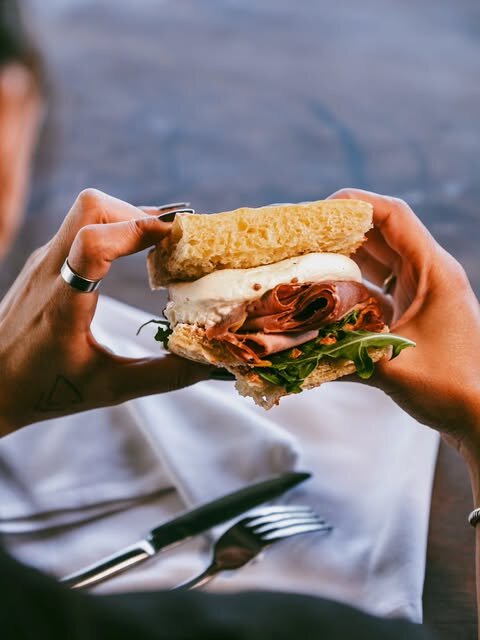 Hands holding a loaded croissant sandwich